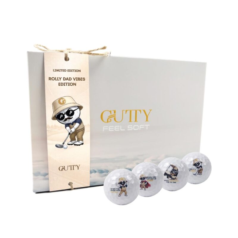 Limited edition golf gift set: gray box with Gutty logo, beige tag reading 'Limited Edition Rolly Dad Vibes Edition,' and four decorated golf balls nearby.