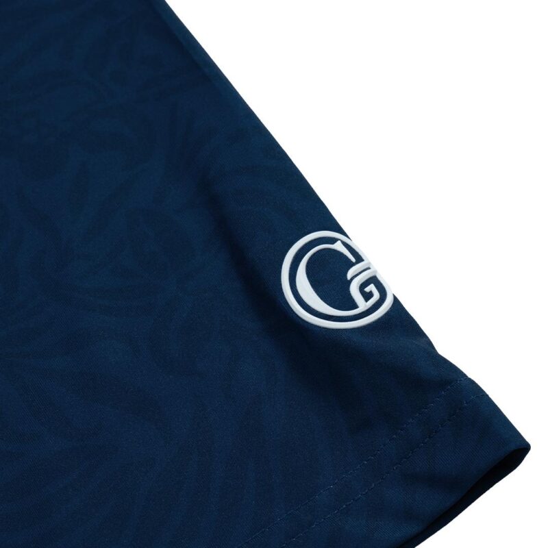 Close-up of navy blue fabric with a white circular logo on the sleeve hem or cuff area.