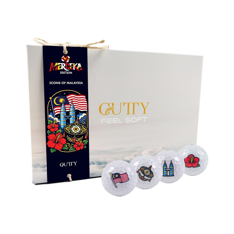 White box with Gutty Feel Soft branding and a dark ribbon featuring Malaysia motifs; four decorative golf balls with Malaysian icons.